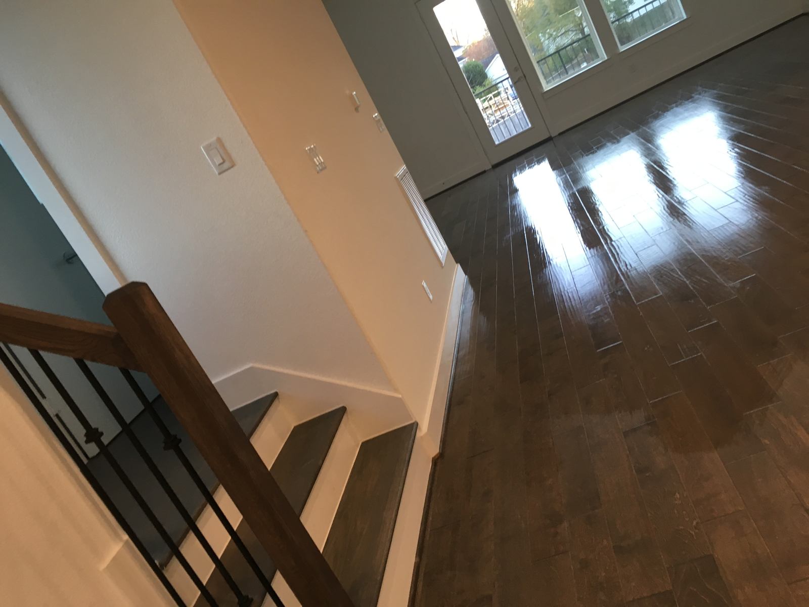 Gleaming wood floors at the top of a staircase with black balusters